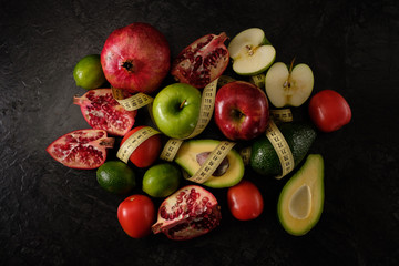 Healthy food. Vegetables and fruits. Measuring tape. On a black background. Top view.