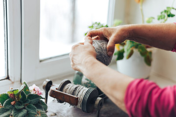 old woman hand making ball with the help of machine for making ball of yarn