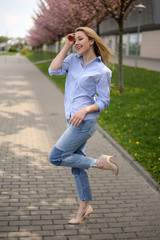 Young blonde hair business woman in shirt and denim pants standing near arrival terminal at the airport