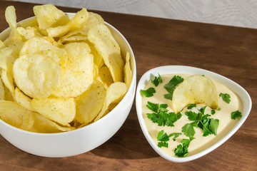Crispy potato chips and fresh mayonnaise with parsley in a white bowls on a table. Fast food and tasty snack consept