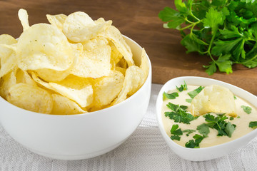 Crispy potato chips and fresh mayonnaise with parsley in a white bowls on a table. Fast food and tasty snack consept
