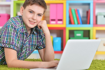 Portrait of boy using laptop while lying on floor