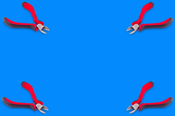 Set of four nippers for wire with red and black handles in corners on blue background with copy...