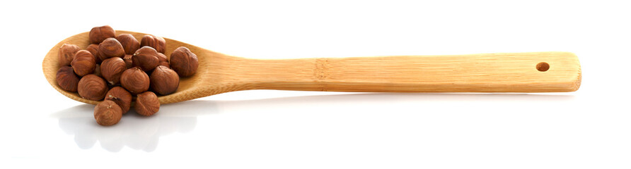 Peeled hazelnut in wooden spoon, on white background, isolated object. Place for Your text.