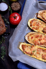 Stuffed zucchini halves roasted with cheese on a black cutting board	