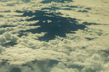 view from a great height on the protruding black tops of the mountains in white clouds