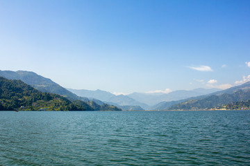 view from the lake to the green mountain valley under the blue sky
