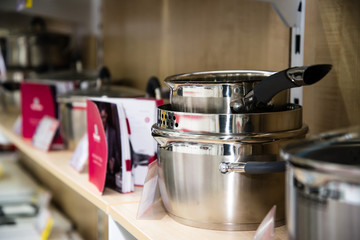 Stainless steel kitchenware set on shelves, shallow depth of field image