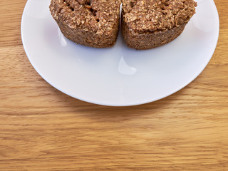 A white plate standing on a wooden table on which there are Two slices of homemade bread. copy space