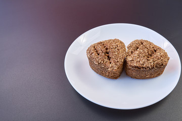 high-quality bread made at home from wheat germ and rye in the shape of a heart. healthy food. natural food. white plate. black background. copy space