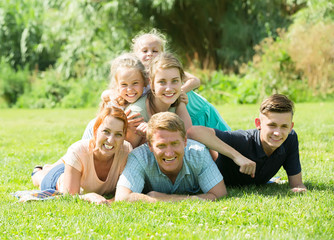 Fototapeta premium Portrait of big friendly family lying on green lawn outdoors