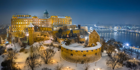 Fototapeta premium Budapest, Hungary - Aerial view of illuminated Buda Castle Royal Palace on a winter night with snowy park and Szechenyi Chain Bridge