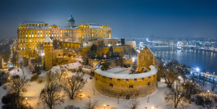 Budapest, Hungary - Aerial view of illuminated Buda Castle Royal Palace on a winter night with snowy park and Szechenyi Chain Bridge
