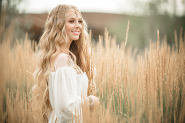 Happy smiling blonde girl is wearing white fashion dress with long blonde hair in field of ray