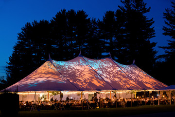 Fototapeta Wedding tent at night - Special event tent lit up from the inside with dark blue night time sky and trees obraz