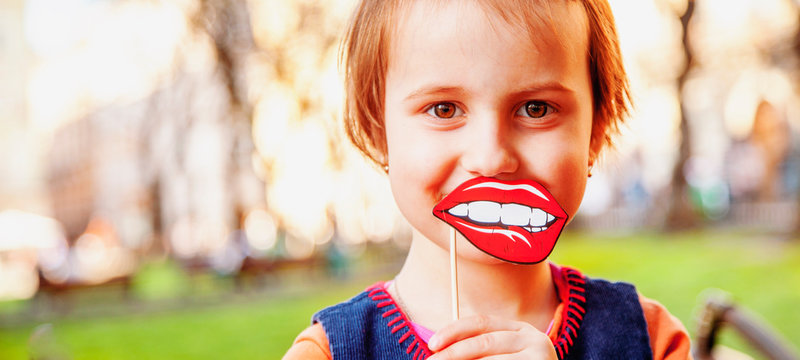 Healthy mental and emotional development concept. Cute little girl try to play roles and emotion with fake lips.