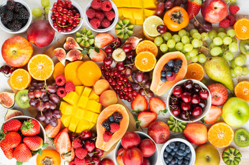Raw fruits bHealthy platter with cut colorful rainbow fruits, strawberries raspberries oranges plums apples kiwis grapes blueberries mango persimmon, copy space, top view, selective focuerries platter