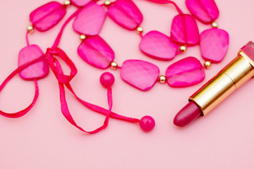 Fashionable pink accessories - beads, lipstick, belt on a gentle pink background. flay lay.
