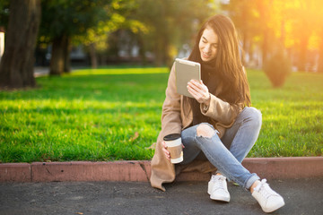 young trendy woman in autumn city park with smartphone in hand