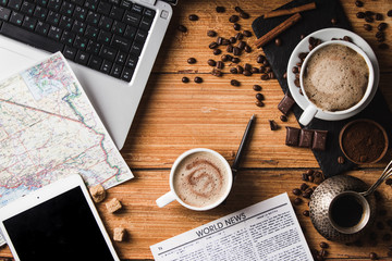 workplace of young freelancer man or woman with coffee, laptop, smartphone in morning on wooden table