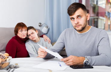 Upset guy with documents and dissatisfied family behind