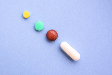 Several different pills types and colors on blue background