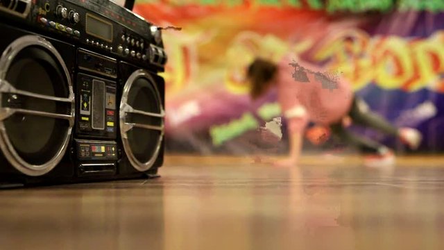 Breakdance dancing girl on graffiti background next to a boombox