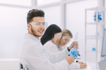 Fototapeta premium young scientist shows a beaker with liquid.