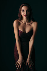 Fototapeta premium Portrait of magnificent sexy woman in evening dress posing over dark green background