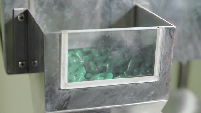 Moving empty two-piece blue-green hard capsules.