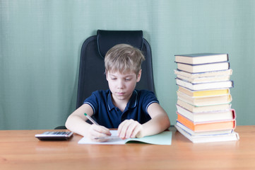 A young boy is working on his homework at the table. Back to school concept. Idea and creativity concept. Copyspace