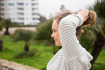 Content woman tying hair in ponytail and wearing sportswear