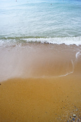 Fototapeta na wymiar Yellow sand on a clean, deserted beach and blue sea waters.
