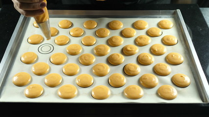 Macaroons squeeze pastry cream or dough on the form on a baking tray