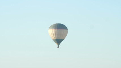 Large balloon in the sun flies against the blue morning sky toward the sun
