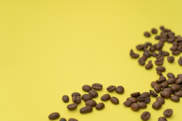 Close-up. Lots of coffee beans scattered on a yellow background.