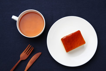 orange honey syrup cake on plate with hot tea isolated on table