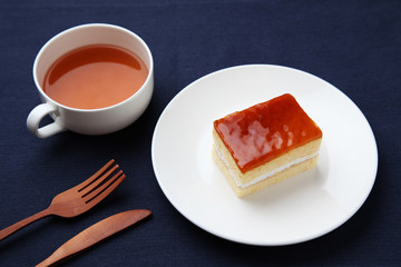 orange honey syrup cake on plate with hot tea isolated on table