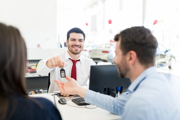 Seller Looking At Couple While Giving Them Car Keys