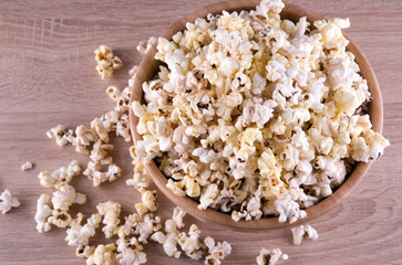 popcorn in a wood cup and on a wood table at a dark background