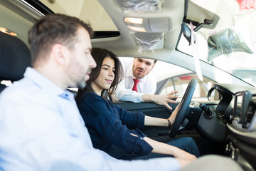 Female Customer Examining Car Interiors With Boyfriend