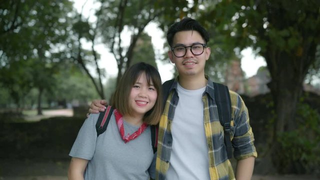 Traveler Asian couple feeling happy smiling to camera holiday trip at Thailand, backpacker sweet couple enjoy their journey at amazing landmark in traditional city. Portrait looking at camera.