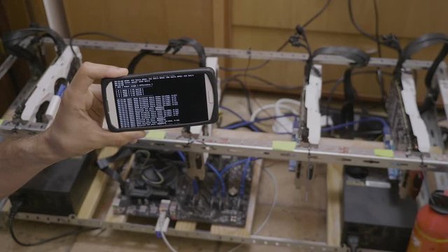 Smartphone software used for mining cryptocurrency rig held by trader
