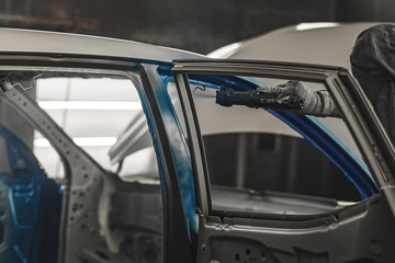 Obraz premium Employee car body painting shop carries out painting of the internal elements of the car