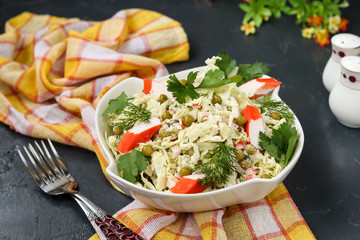 Healthy salad with Chinese cabbage, canned peas and crab sticks in a bowl against a dark background