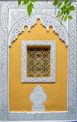 Typisches, altes, reich verziertes, kunstvoll geschnitztes, mit Nieten besetztes, marokkanisches Riad, gelbes Fenster und Rahmen und altes Haus. Schöne Aussicht auf die blaue Wand in der Medina. Bemalte Häuser in Marrakesch, Marokko © mitzo_bs