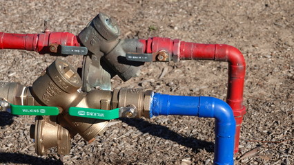 Red and blue water lines with backflow preventer - obrazy, fototapety, plakaty
