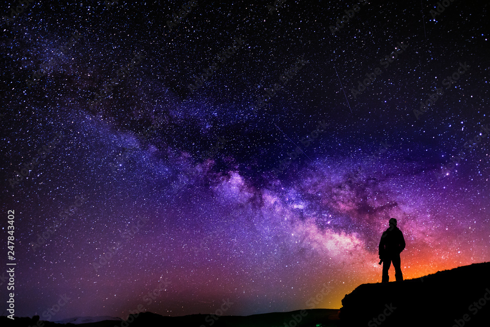 Wall mural beautiful starry night, man silhouette with a camera looking at the milky way galaxy.