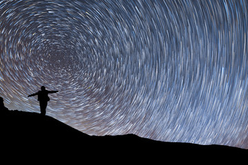 Beautiful starry night, female silhouette a standing with raised up arms on the mountain . Night...