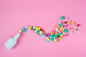 White, yellow, red, blue pills, tablets and white bottle on pink background